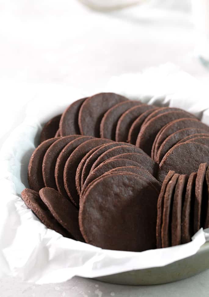 crispy round chocolate sugar cookies in stacks on their sides in white paper